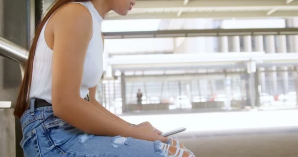 Teenage girl using mobile phone at bus stop 4k - Footage, Video