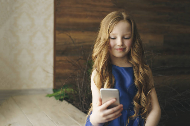 dzieci, technologii i komunikacji koncepcja - uśmiechnięta dziewczyna SMS-y na smartfonie w domu - Zdjęcie, obraz