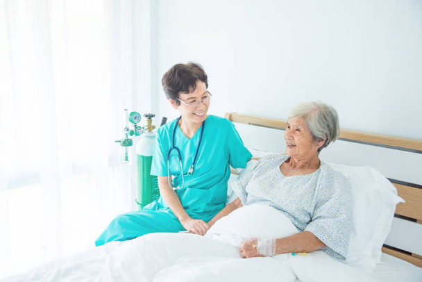 Vanhempi naispotilas hymyilee sairaanhoitajan kanssa, joka tulee käymään
 - Valokuva, kuva