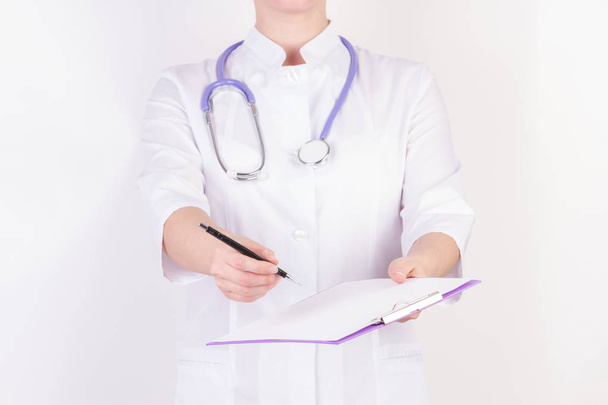 Doctor in white robe with stethoscope, with folder in hand, on white isolated background. - Foto, afbeelding
