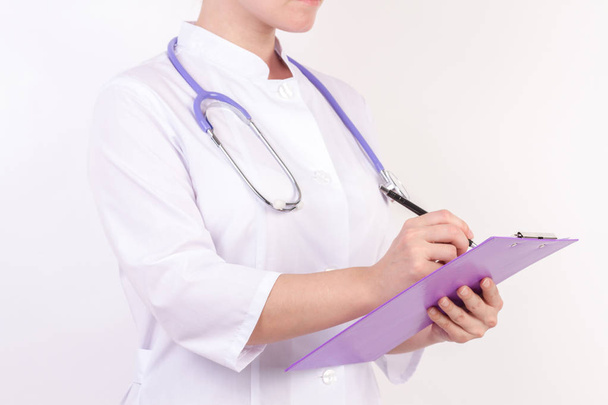 Doctor in white robe with stethoscope, with folder in hand, on white isolated background. - Foto, imagen