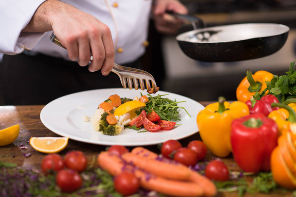 chef serving vegetable salad on plate in restaurant kitchen - Foto, imagen