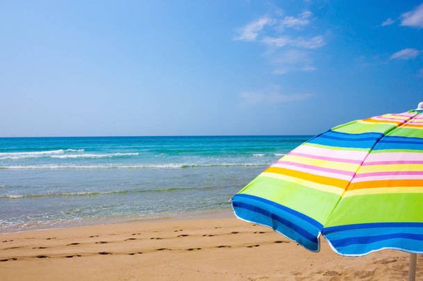 Barevný deštník na písečné pláži slunečného dne - Fotografie, Obrázek