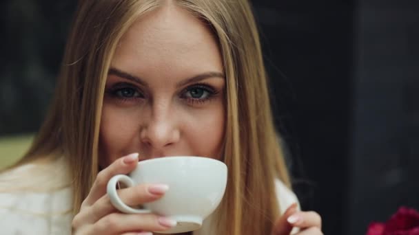 Adorable young woman drinks her coffee sitting in the cafe - Video