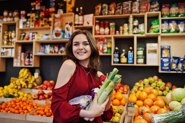 Lány piros gazdaság különböző zöldségek, gyümölcsök Store. - Fotó, kép