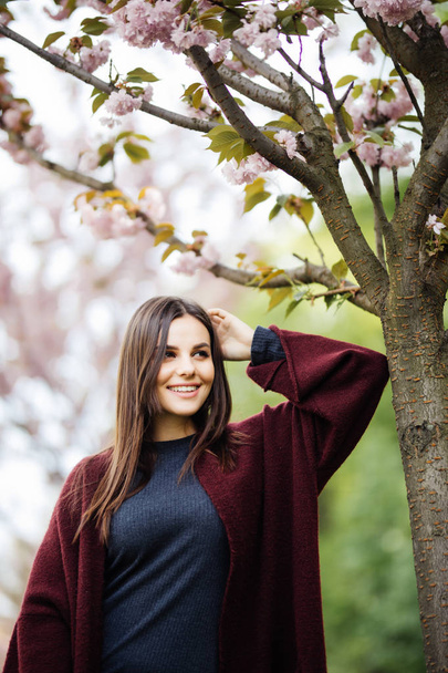 Girl with sakura tree flowers. Focus on face. Spring concept - Foto, afbeelding