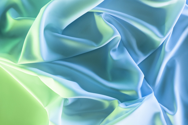 getöntes Bild von grünen und blauen weichen Seidentüchern als Hintergrund - Foto, Bild