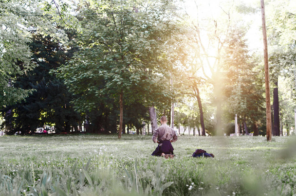 Rear view of young man meditating in park - Foto, Bild