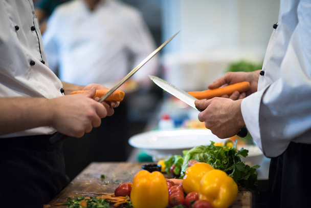 chefs mãos cortando cenouras em uma mesa de madeira preparação para refeição no restaurante
 - Foto, Imagem