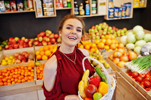 Girl in red holding different fruit and vegetables at basket on  - Foto, Bild