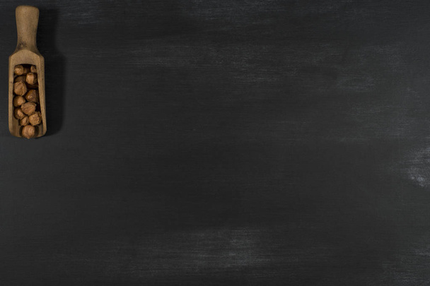 Hazelnut scoop on black chalkboard.  - Фото, изображение