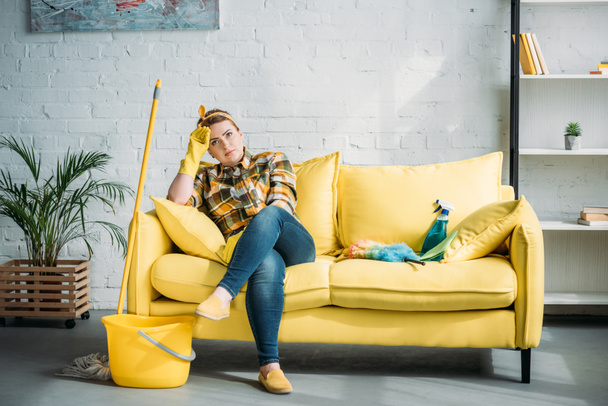 втомлена красива жінка сидить на дивані після прибирання вдома
 - Фото, зображення