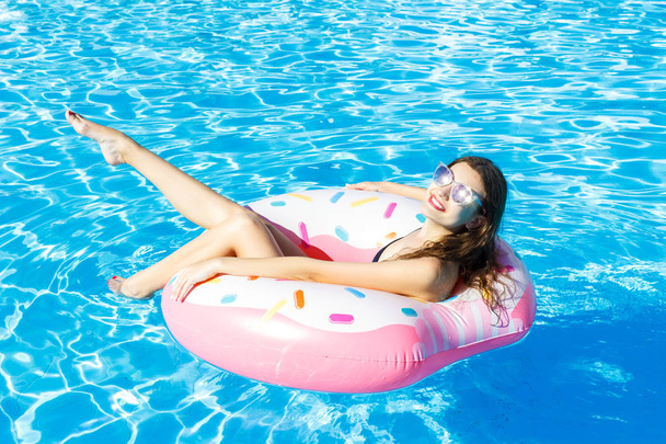 вид зверху на молоду жінку, що плаває з рожевим колом у басейні
 - Фото, зображення