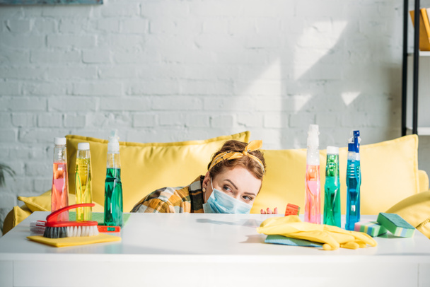beautiful woman looking out from table with cleaning supplies at home - Photo, image