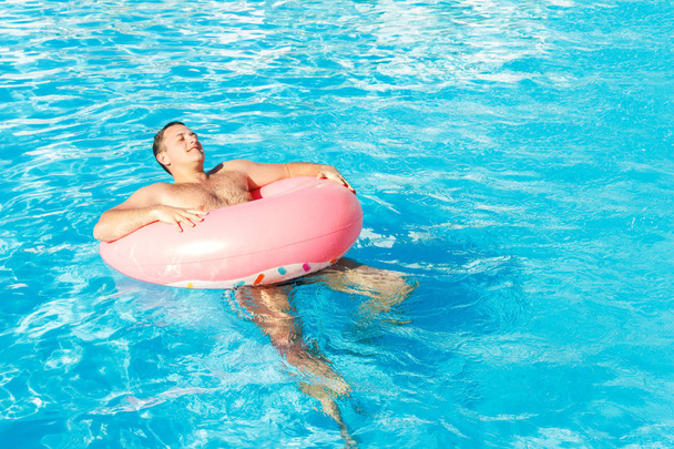 Beautiful young man relaxing in pool. vacation concept with space for text. Top view - 写真・画像