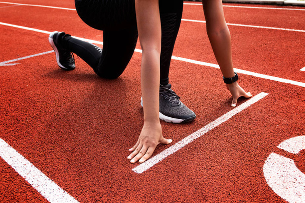 Female athlete on the starting line of a stadium track preparing - Photo, Image