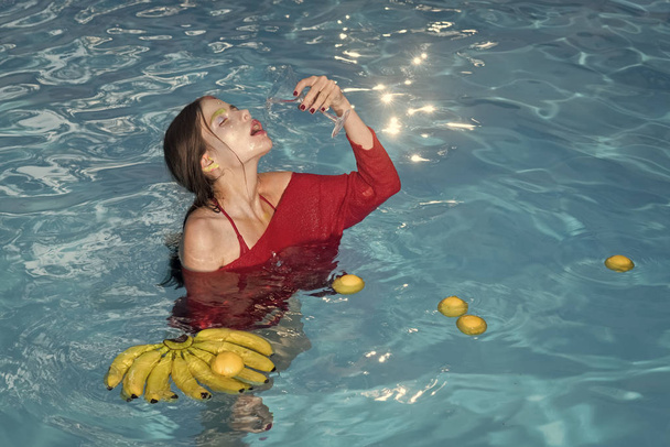 Zomervakantie en reizen naar de Oceaan. zomer splash en fruit mengen bij girl zwemmen in zwembad drinken uit glas - Foto, afbeelding