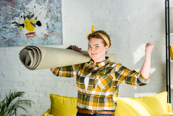 piękna kobieta, trzymając dywan na ramieniu i Wyświetlono mięśnie w domu - Zdjęcie, obraz