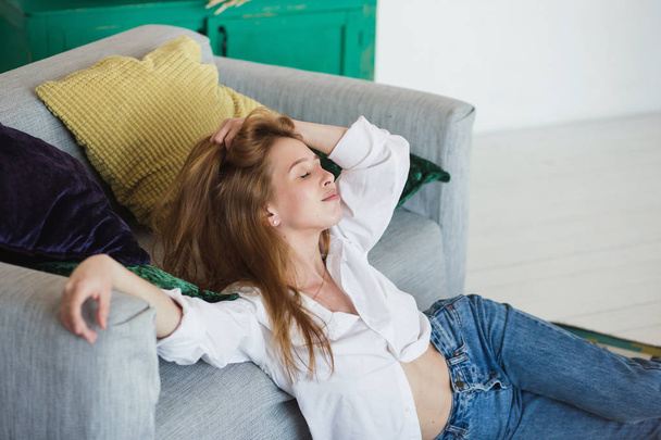 Young woman relaxing at cozy sofa in light room - Fotó, kép