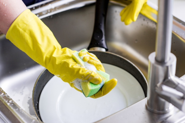 imagen recortada de la mujer lavando platos y sosteniendo la esponja de lavado en la cocina
 - Foto, Imagen