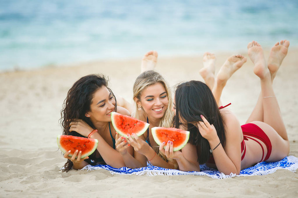 Barátnők enni görögdinnye, és élvezi a nap a strandon - Fotó, kép