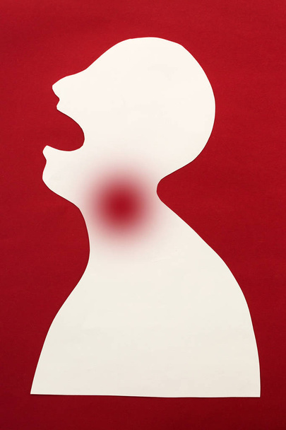 concept of human disease diagnosis and pain localization on silhouette - contour of abstract white man with opened mouth and severe pain in the throat, isolated on red background, top view, flat lay - Foto, imagen