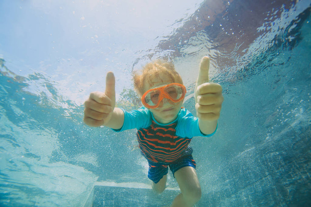 маленький хлопчик плаває під водою з великими пальцями вгору
 - Фото, зображення