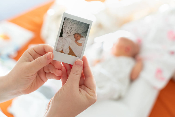 Ensimmäinen kuva vastasyntyneestä naisäidin käsissä lasta vastaan. Instant Photo tyyliin Polaroid raskaan paperin
. - Valokuva, kuva