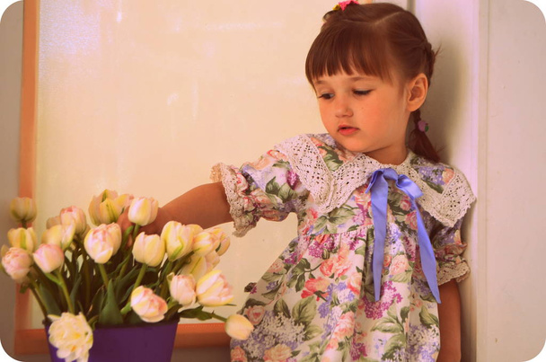 Little girl with beautiful tulips - Foto, afbeelding