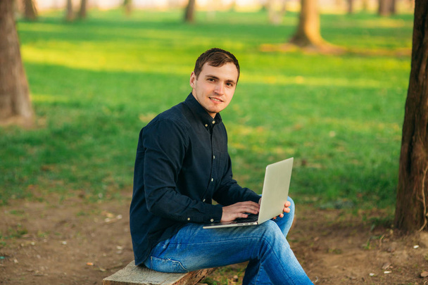 De jonge manager werken op een laptop in het park. Lunchpauze - Foto, afbeelding