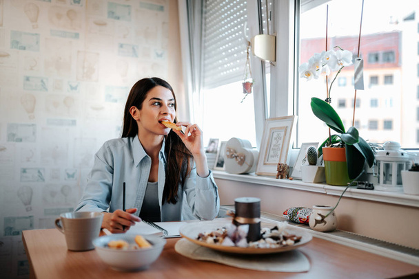 Beautiful brunette woman having breakfast in her apartment. - Foto, Imagen