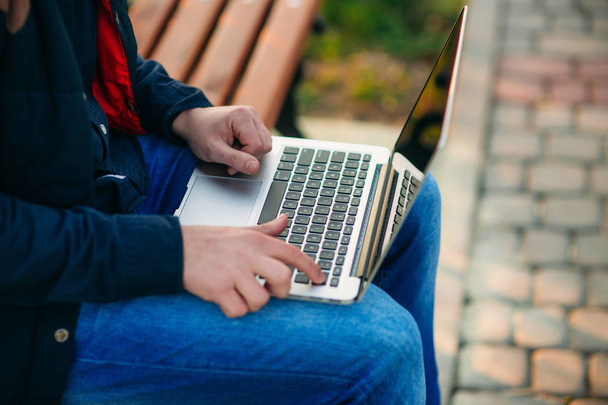 Jeune homme assis sur le banc avec ordinateur portable
 - Photo, image