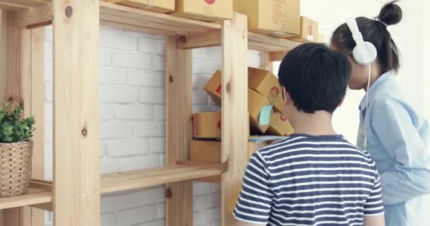 junge asiatische Frau mit Kind arbeitet und packt thailändischen Briefkasten zu senden, junge Unternehmen gründen. sme, Lieferprojekt, - Filmmaterial, Video