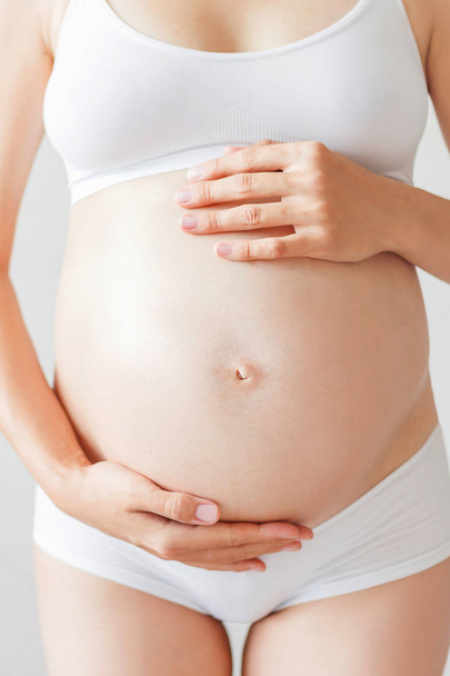 Mulher grávida em roupa interior branca. Jovem mulher esperando um bebê. - Foto, Imagem