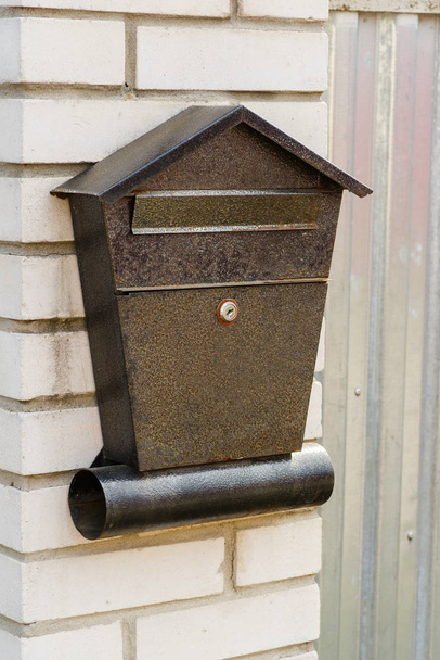 Metallinen postilaatikko tiiliseinällä roikkuu
 - Valokuva, kuva