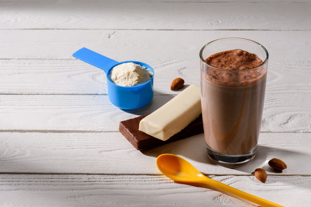 glass of protein shake with energy bars on white wooden table - Photo, Image
