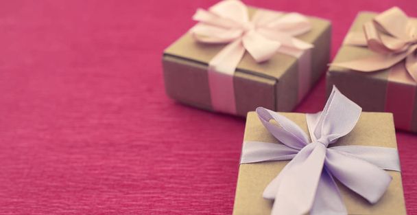 Банер Святкова композиція три крафт коробки з подарунками на яскраво-рожевому тлі
. - Фото, зображення