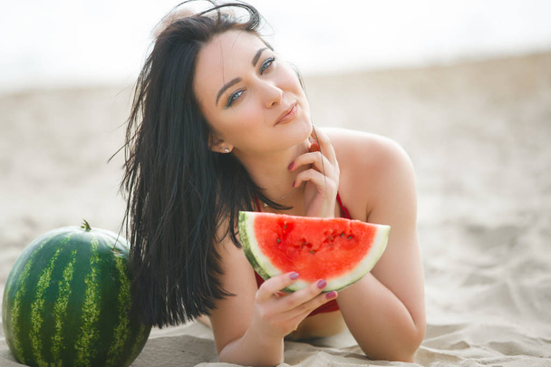 Young attractive woman on the beach relaxing. Pretty woman with watermelon. Cute girl outdoors - Фото, изображение