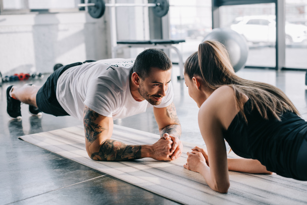 male personal trainer and sportswoman doing plank at gym - Zdjęcie, obraz