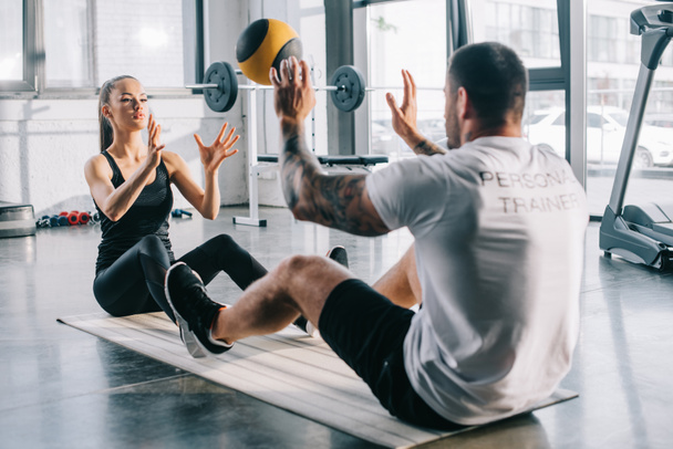 male personal trainer and sportswoman doing exercises with ball at gym - Zdjęcie, obraz