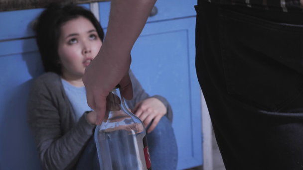 Smutné, osamělé asijské dívka sedící na podlaze v kuchyni, drží kolena s zbraní, pojem domácí násilí, opilý manžel jde porazit svou ženu 50 fps - Záběry, video