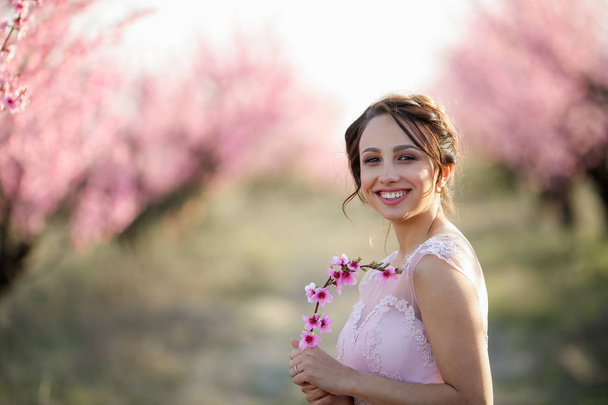 beautiful bride posing in the garden against blossoming trees  - Fotó, kép