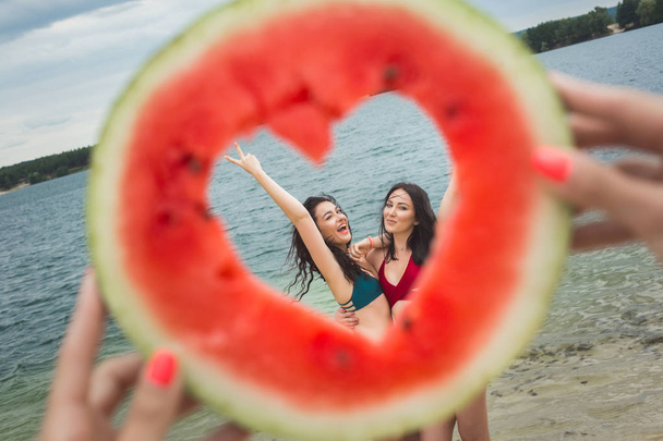 Молодые привлекательные веселые женщины на пляже веселятся с арбузом
 - Фото, изображение