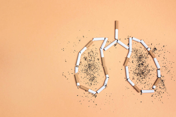 Broken cigarettes and tobacco in the form of lungs on yellow bac - Photo, Image