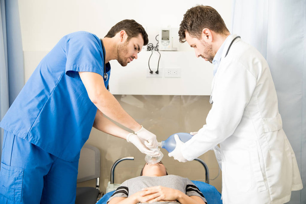 Deux médecins pratiquant une RCR sur une patiente utilisant un sac ambu dans un hôpital
 - Photo, image