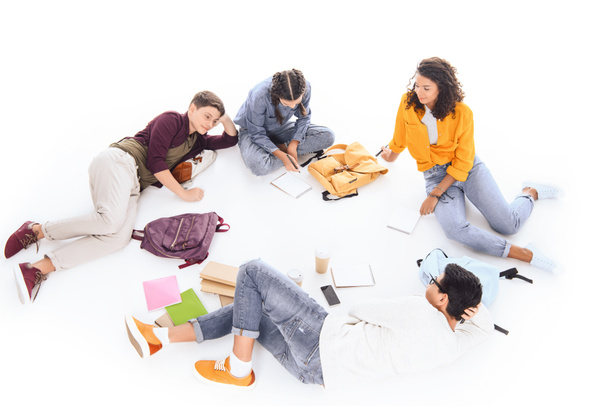 high angle view of interracial students with notebooks and backpacks resting isolated on white - 写真・画像