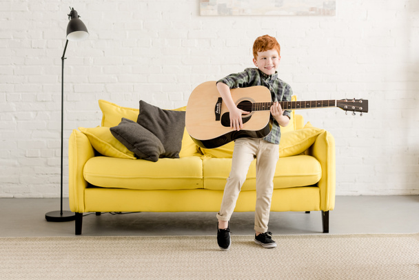 adorable happy little boy playing guitar at home - Foto, Bild