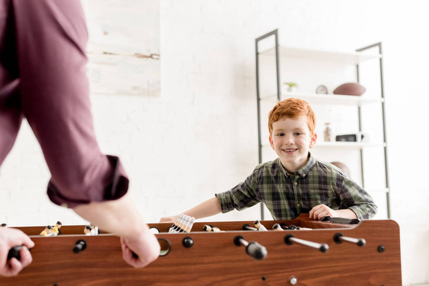 cropped shot of father and cute smiling son playing table football together at home  - Foto, afbeelding