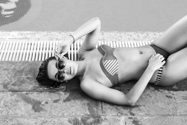 Pretty brunette girl sunbathing at the swimming pool - Foto, Bild