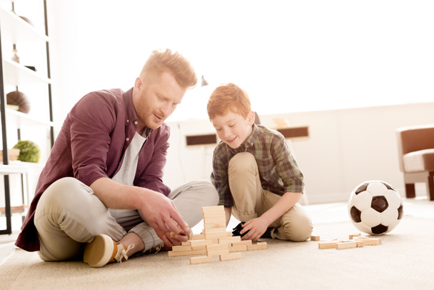 uśmiechnięty ojciec i syn, grając z drewnianych klocków w domu - Zdjęcie, obraz